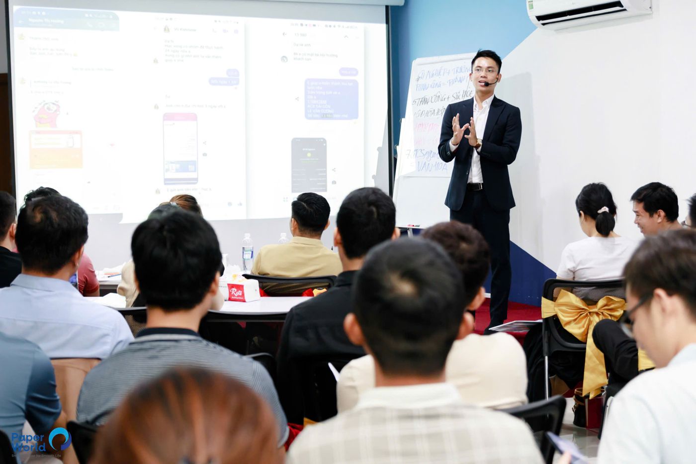 Cương đứng lớp với màn hình trình chiếu phía sau. Từ 2026, nội dung trên màn hình đó không còn chỉ là slide, mà là những AI Agent học viên tự dựng.