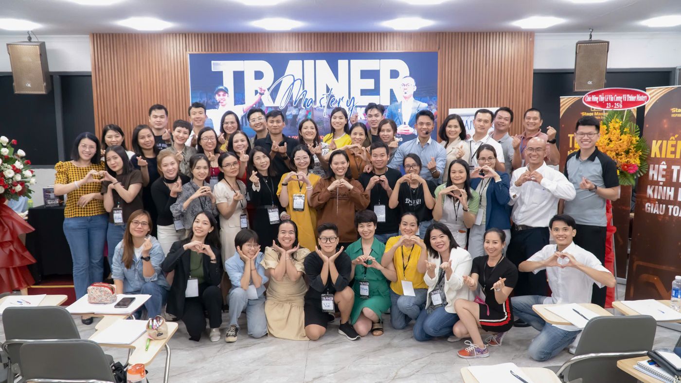 Ảnh tập thể Trainer Mastery khoá 14. Phương pháp bốn bước Thu hút, Ảnh hưởng, Giá trị, Chuyển hoá của chương trình này vẫn là nền, AI Agent là lớp nhân bản phía trên.